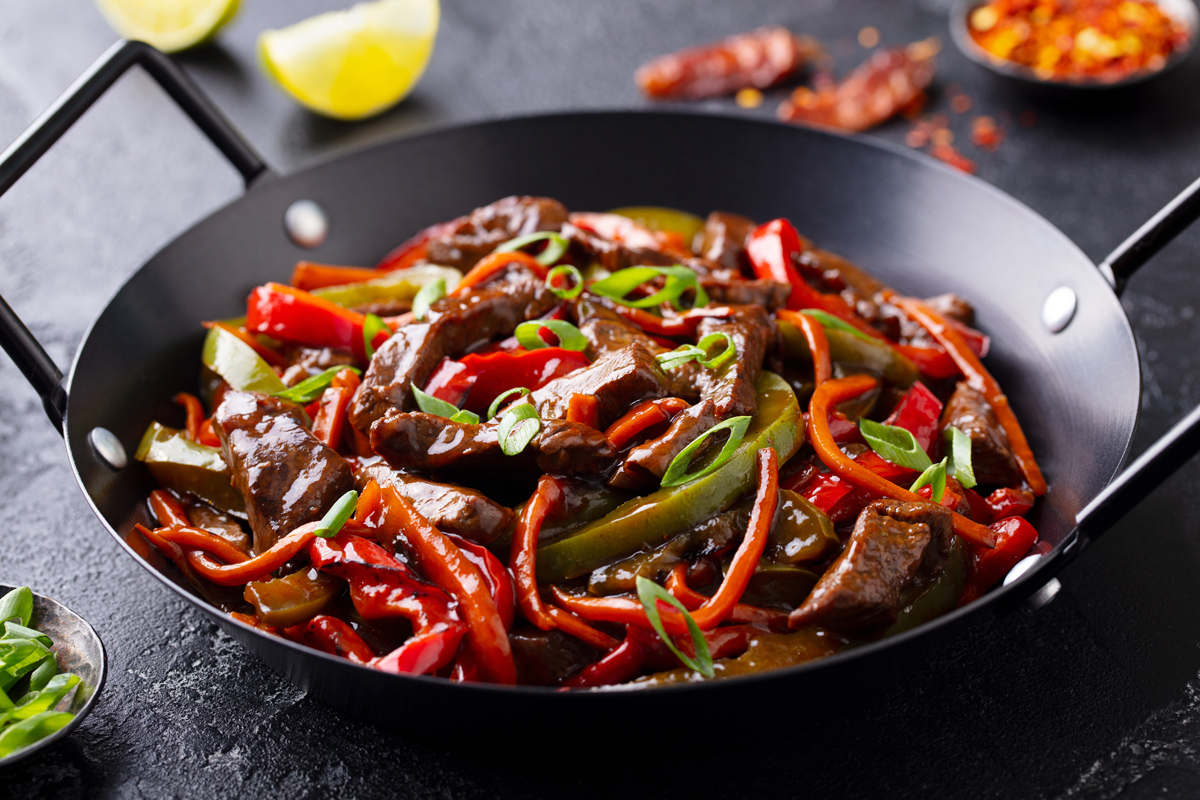 Beef and vegetables stir fry in a pan Dark background Close up