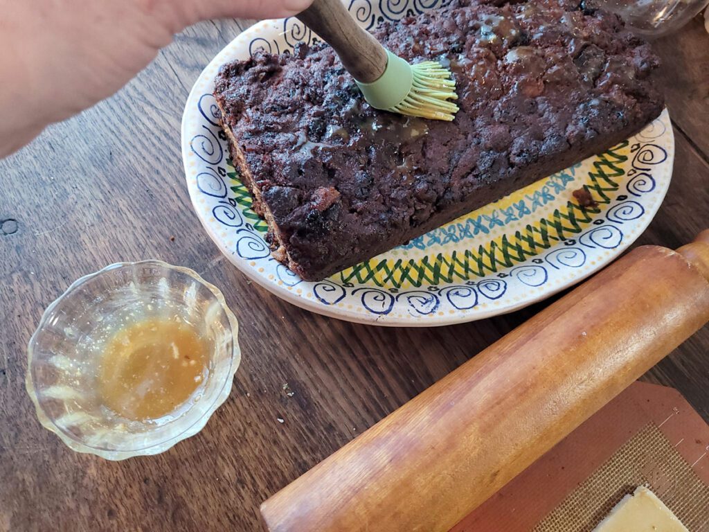 Painting fruitcake with caramel to "glue" marzipan to it