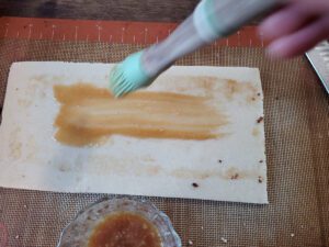 Painting marzipan with caramel to "glue" it to a fruitcake