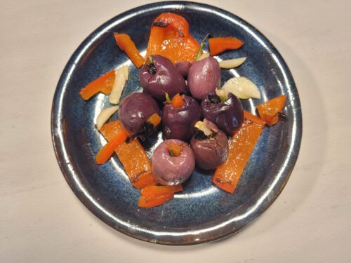 Garlic-stuffed olives with red pepper and rosemary to be served cold