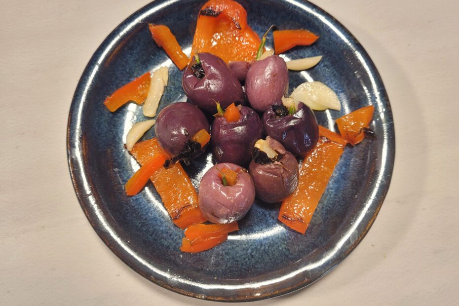 Garlic-stuffed olives with red pepper and rosemary to be served cold