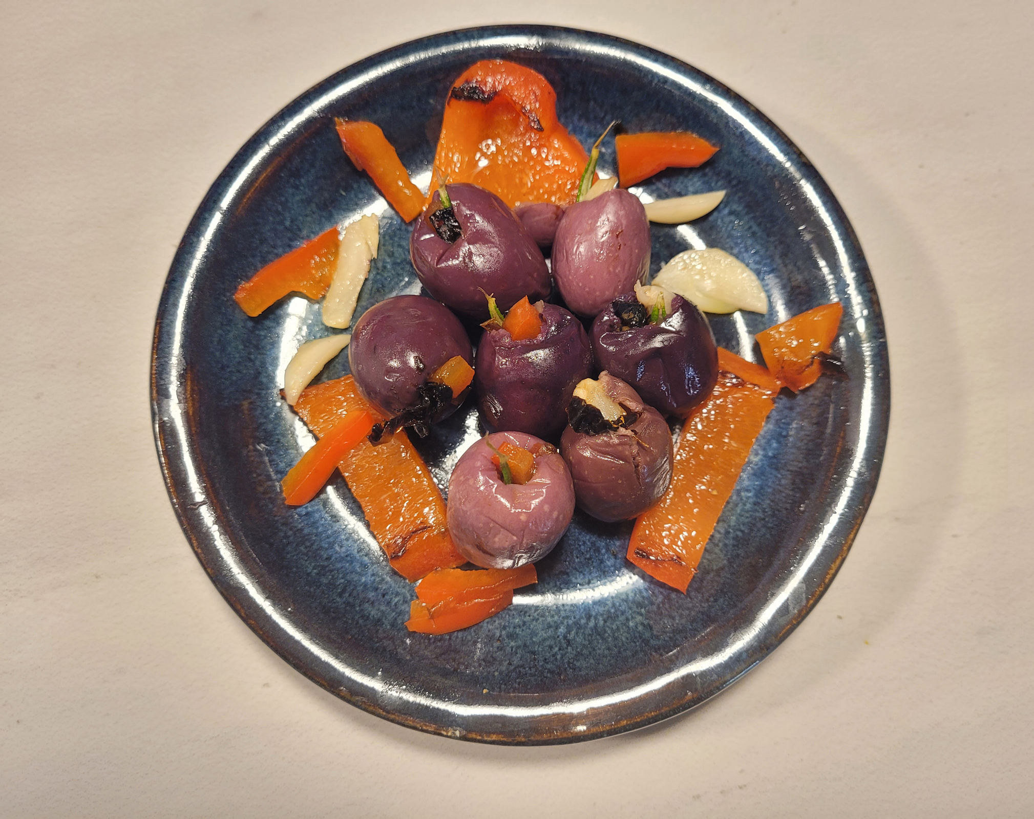 Garlic-stuffed olives with red pepper and rosemary to be served cold