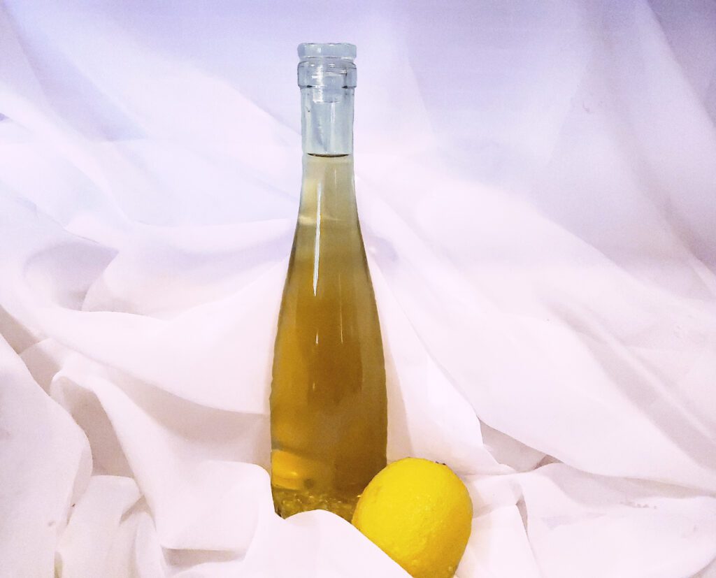 Bottle of limoncello with a lemon on a gauze background